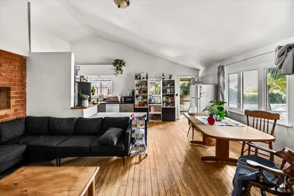 a living room with furniture and a dining table with wooden floor