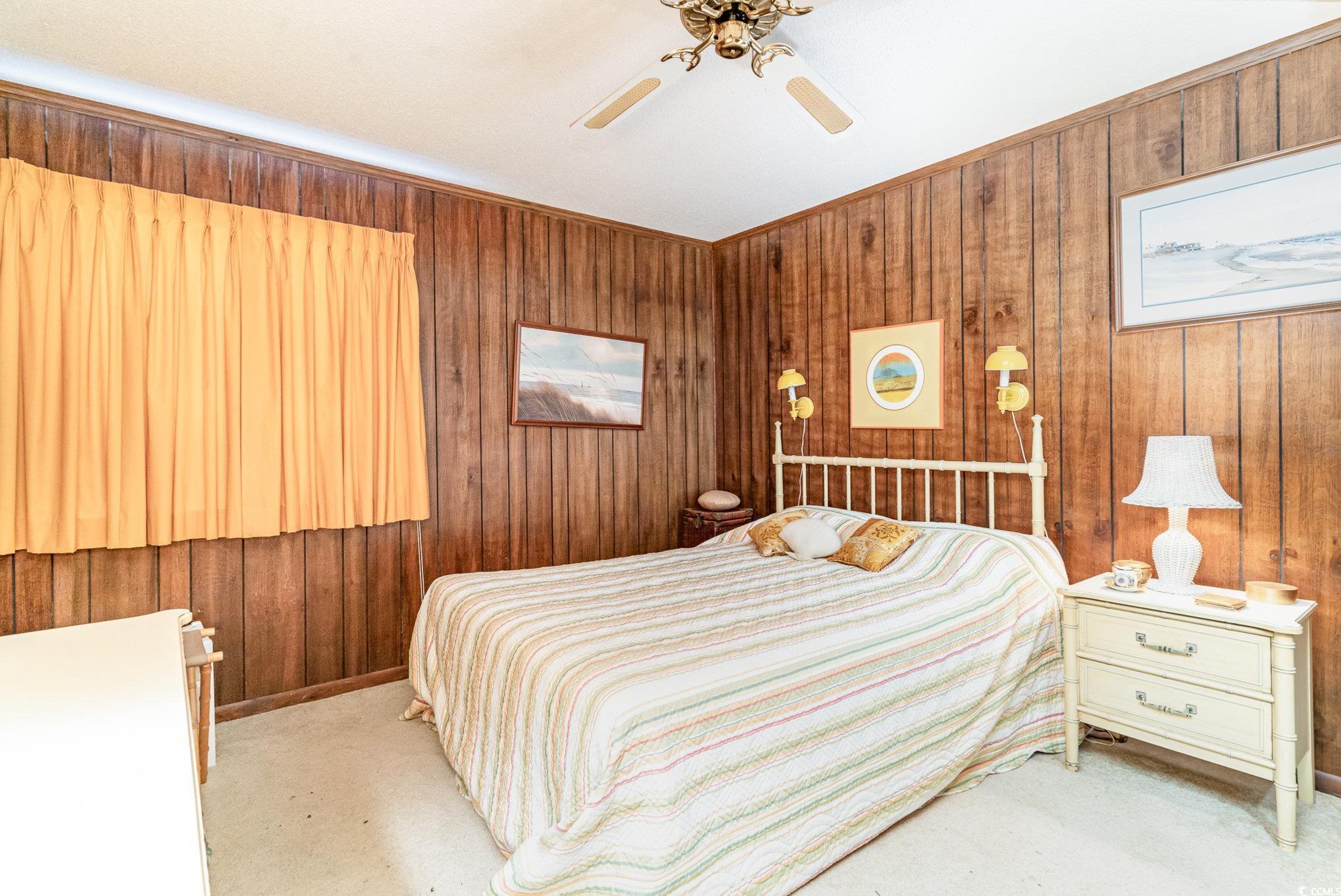 1582 South Waccamaw Drive, Unit 60 Murrells Inlet, SC 29576 - Photo 11 of 24 Bedroom with ceiling fan, light colored carpet, and wood walls