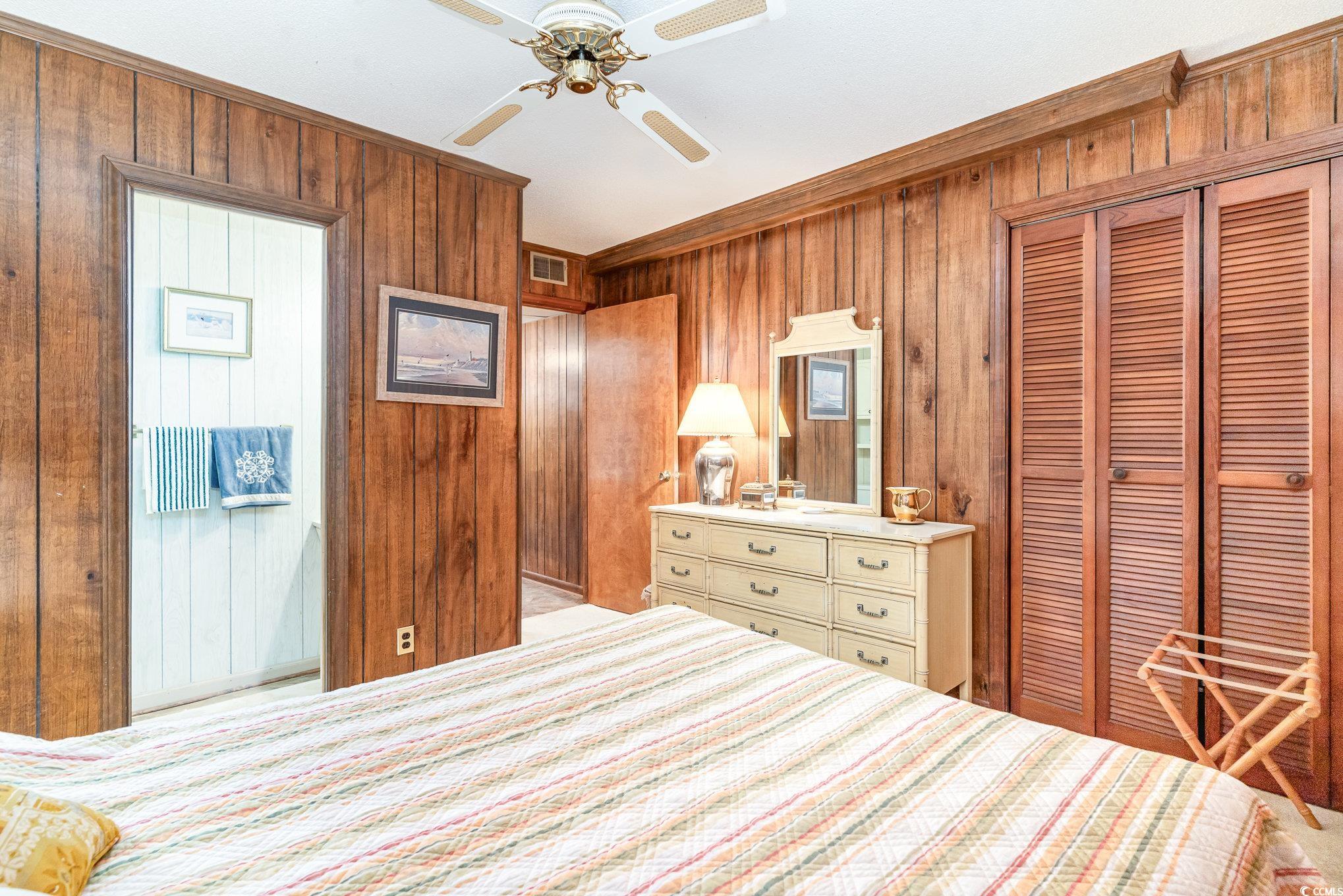 1582 South Waccamaw Drive, Unit 60 Murrells Inlet, SC 29576 - Photo 12 of 24 Bedroom with ornamental molding, ceiling fan, wood walls, and a closet