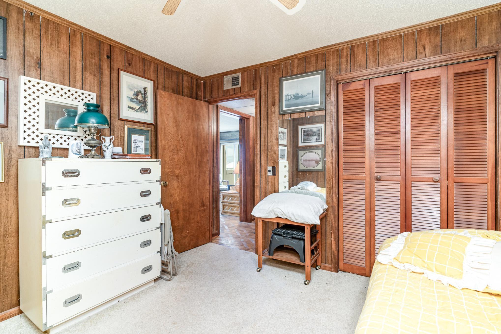 1582 South Waccamaw Drive, Unit 60 Murrells Inlet, SC 29576 - Photo 9 of 24 Bedroom with light carpet, wooden walls, ceiling fan, and a closet