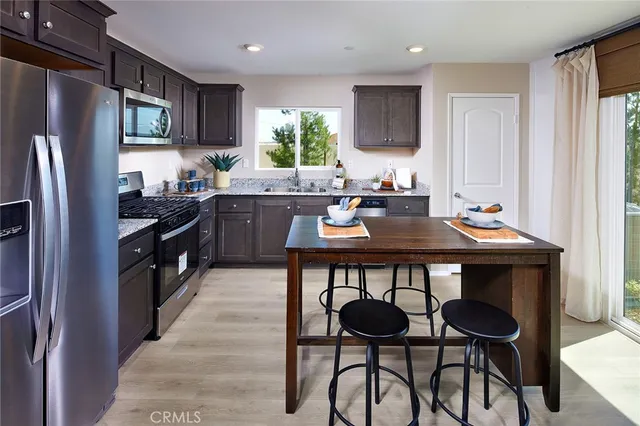 a kitchen with stainless steel appliances a table chairs refrigerator and microwave