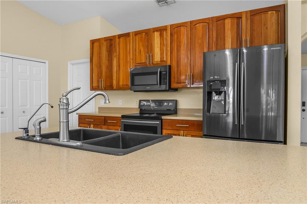 2905 Northeast 1st Place Cape Coral, FL 33909 - Photo 5 of 32 a kitchen with granite countertop a refrigerator and a sink