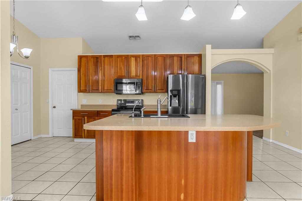 2905 Northeast 1st Place Cape Coral, FL 33909 - Photo 8 of 32 a kitchen with kitchen island a counter top space cabinets and stainless steel appliances