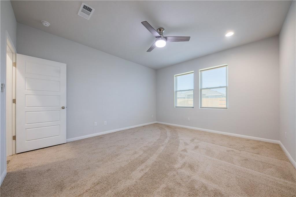 204 Cold Spg Loop Bastrop, TX 78602 - Photo 14 of 34 Expansive room featuring plush carpet flooring, two windows, a ceiling fan with integrated lighting, recessed lighting, and a contemporary five-panel interior door