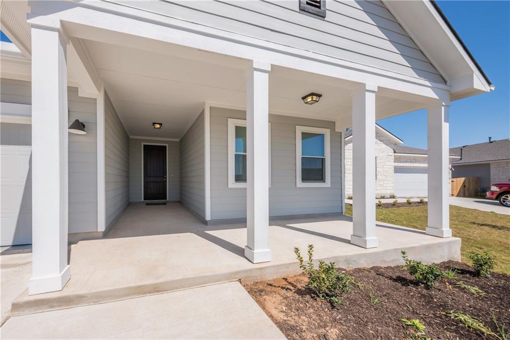 204 Cold Spg Loop Bastrop, TX 78602 - Photo 2 of 34 Covered front entry featuring a dark wood-finish door, sconce lighting, and a window with white trim