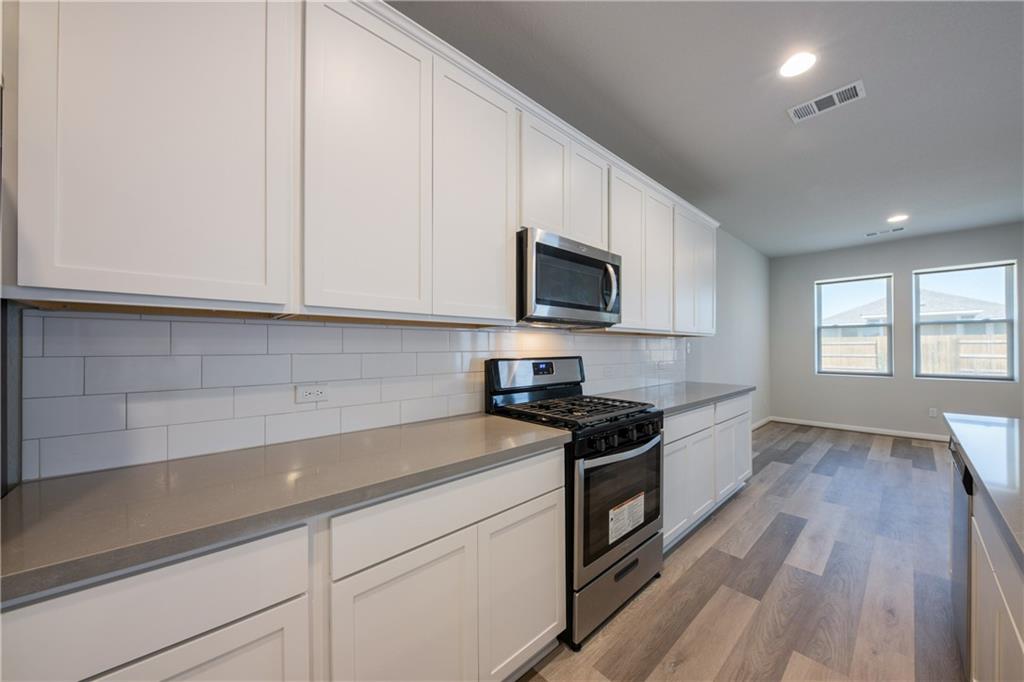204 Cold Spg Loop Bastrop, TX 78602 - Photo 22 of 34 Modern kitchen featuring white shaker cabinetry, stainless steel appliances, a subway tile backsplash, and light grey countertops
