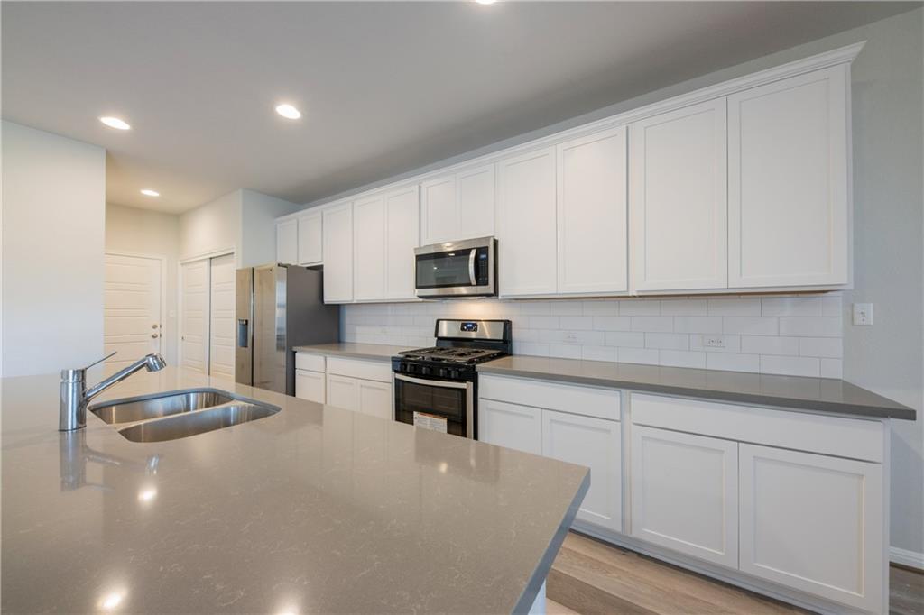 204 Cold Spg Loop Bastrop, TX 78602 - Photo 23 of 34 Modern kitchen featuring an expansive island with a double basin stainless steel sink and gooseneck faucet