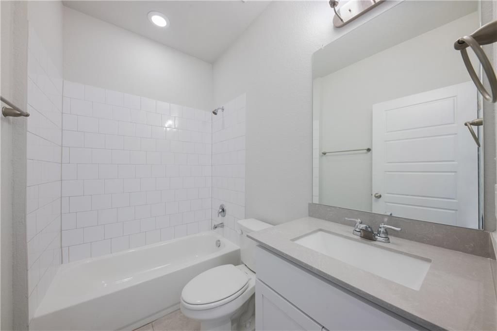 204 Cold Spg Loop Bastrop, TX 78602 - Photo 30 of 34 Bathroom featuring a white subway tile shower surround, a white bathtub, and a vanity with a light-colored countertop