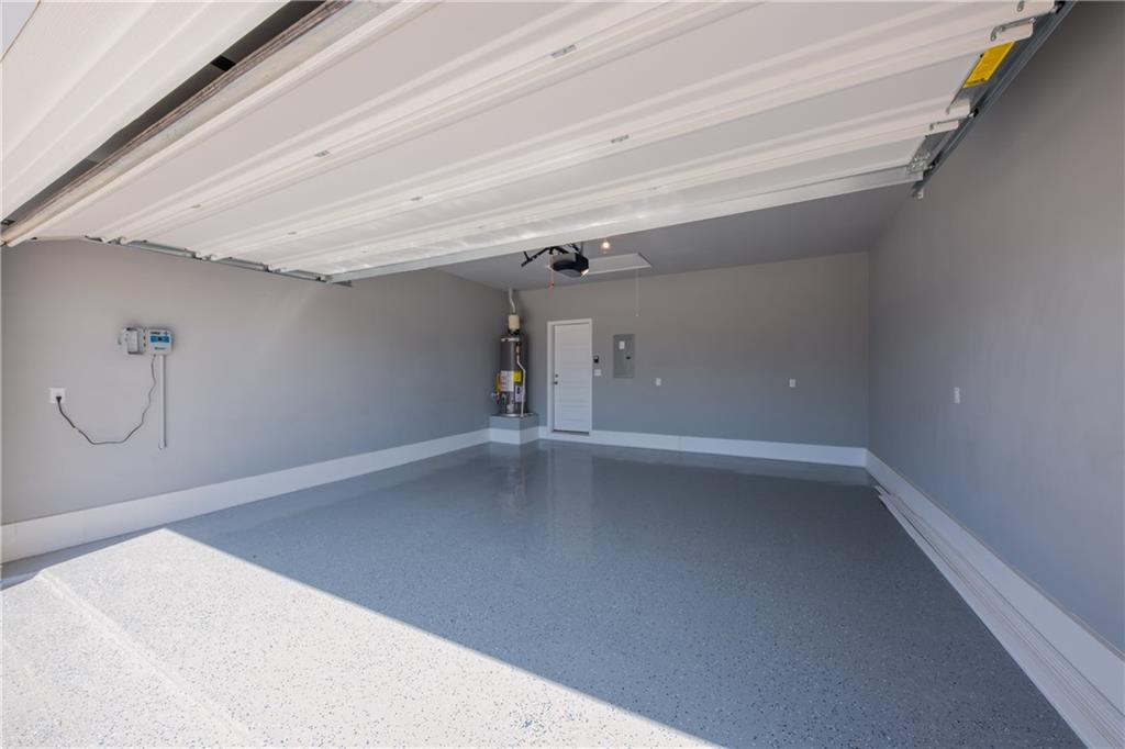 204 Cold Spg Loop Bastrop, TX 78602 - Photo 5 of 34 Spacious garage featuring an epoxy-finished floor, light gray walls, white baseboards, and a white overhead garage door