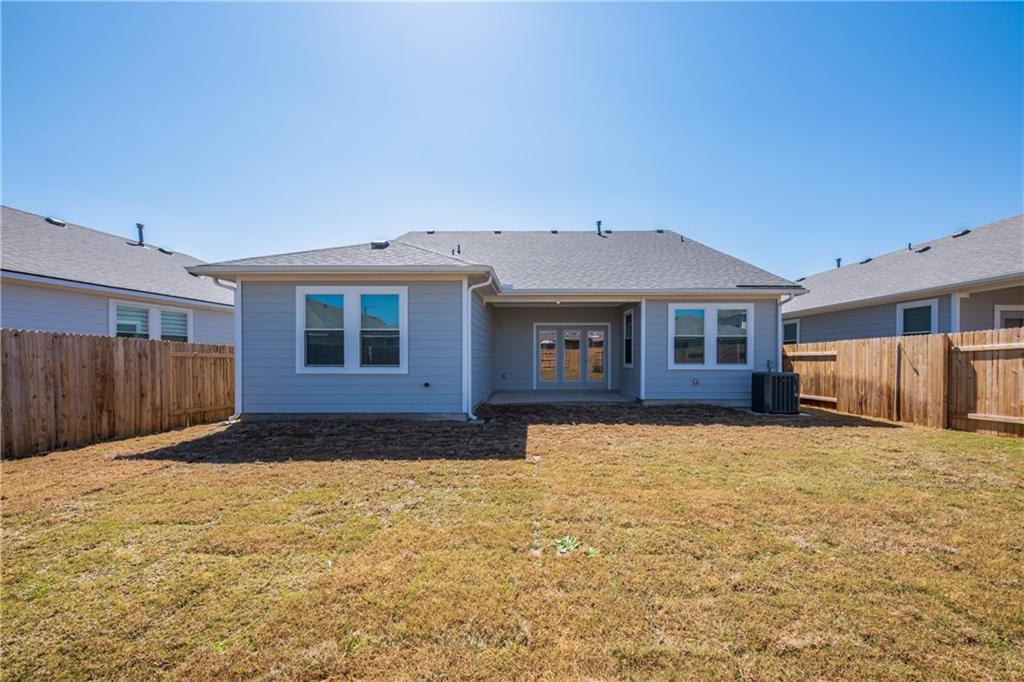 204 Cold Spg Loop Bastrop, TX 78602 - Photo 6 of 34 Rear exterior featuring a covered patio, double French doors, multiple windows, gray siding, and a fenced perimeter
