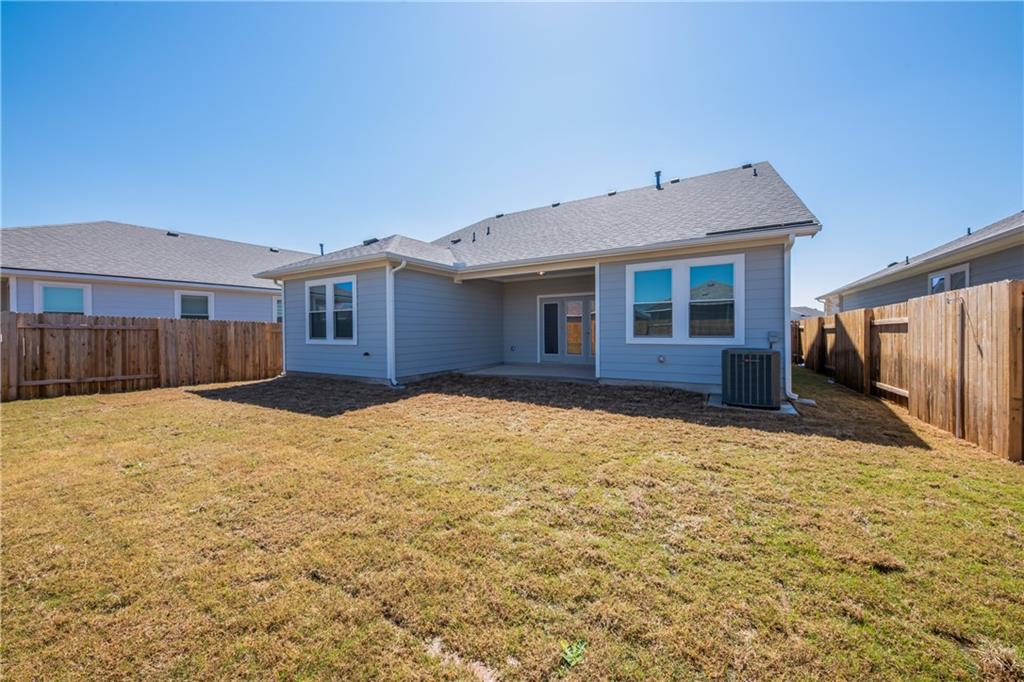 204 Cold Spg Loop Bastrop, TX 78602 - Photo 7 of 34 Expansive backyard featuring a partial privacy fence, a concrete patio, and a light-colored siding exterior