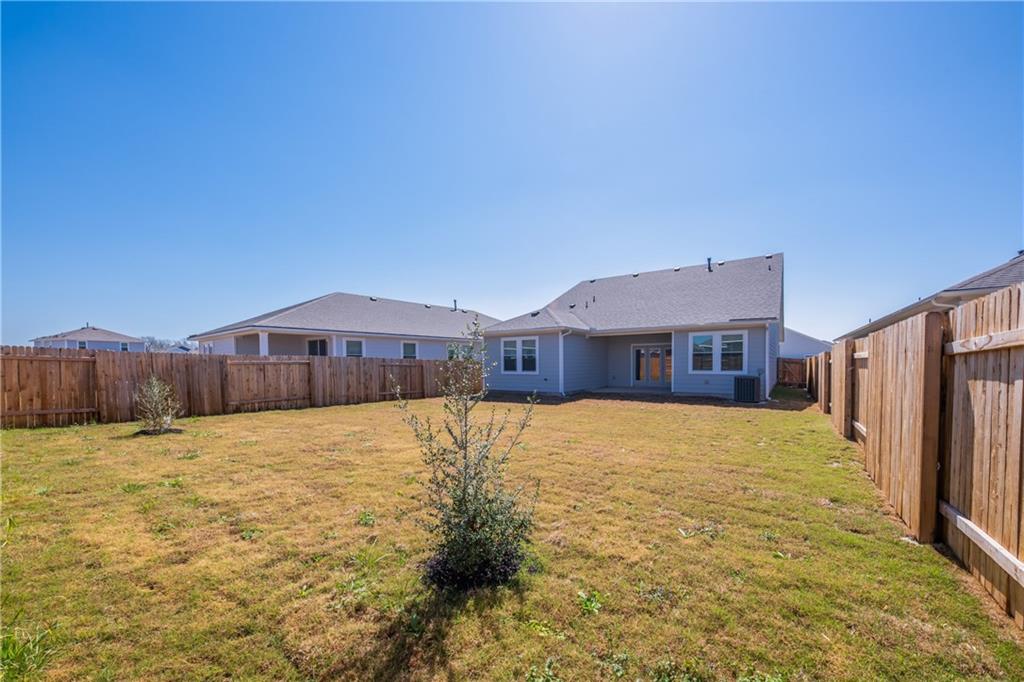 204 Cold Spg Loop Bastrop, TX 78602 - Photo 10 of 34 Spacious backyard featuring a full perimeter wood privacy fence, light gray exterior siding, white window trim, and a covered back patio