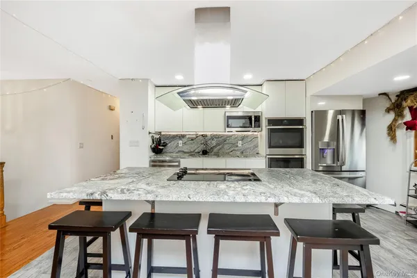 a kitchen with granite countertop a table chairs stove and refrigerator