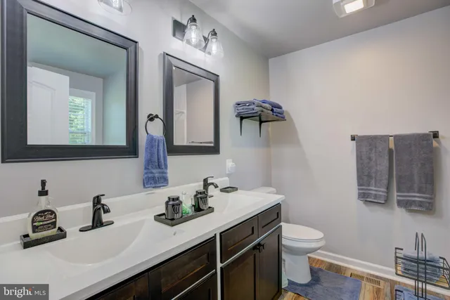 a bathroom with a toilet sink double vanity and mirror