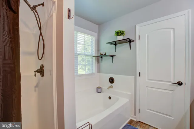 a bathroom with a bathtub a window and a shower