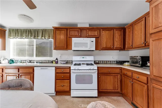 a kitchen with stainless steel appliances granite countertop a stove top oven a sink dishwasher and white cabinets with wooden floor