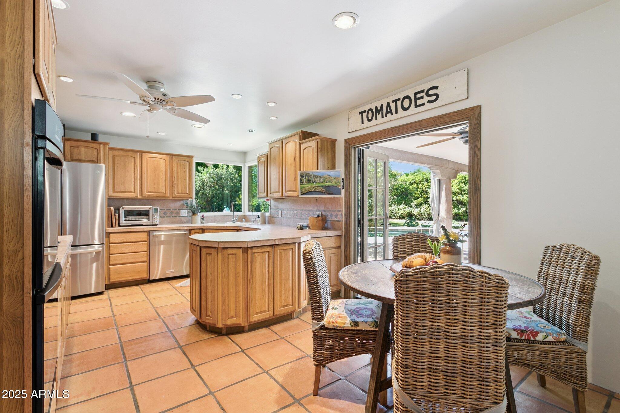 7005 East Jackrabbit Road Paradise Valley, AZ 85253 - Photo 15 of 61 a kitchen with a refrigerator a stove a sink dishwasher a dining table and chairs with wooden floor