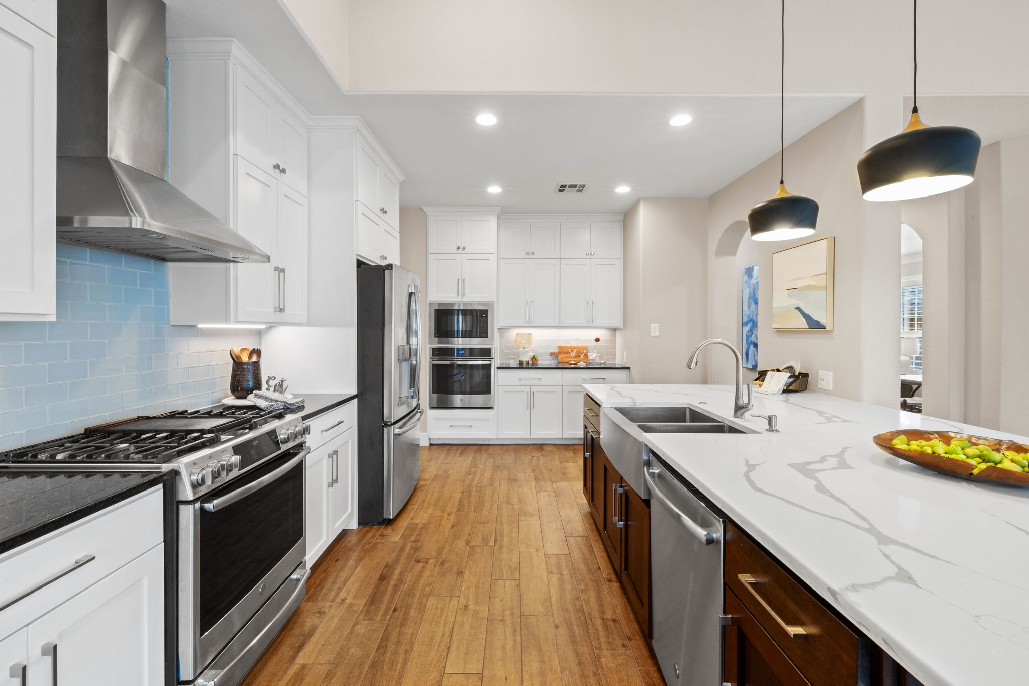 8112 Cobblestone Austin, TX 78735 - Photo 11 of 33 Kitchen with wall chimney exhaust hood, appliances with stainless steel finishes, arched walkways, light wood finished floors, and recessed lighting