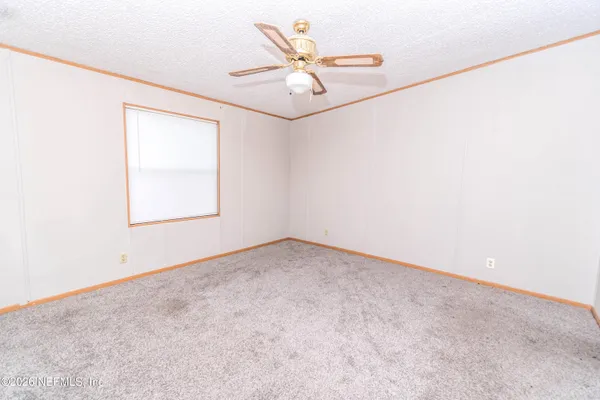 an empty room with a window and a ceiling fan