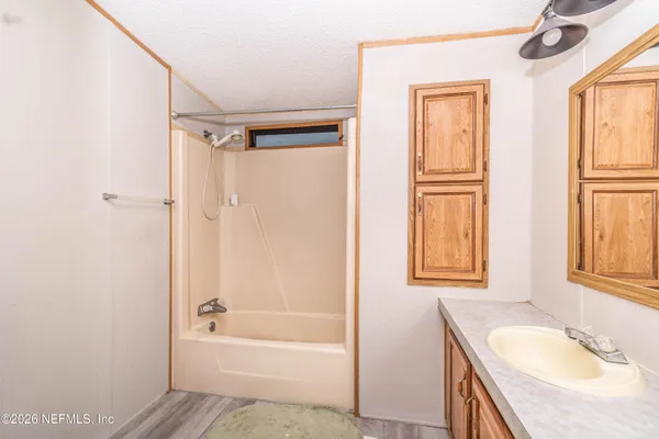 a bathroom with a granite countertop sink a mirror bathtub and shower