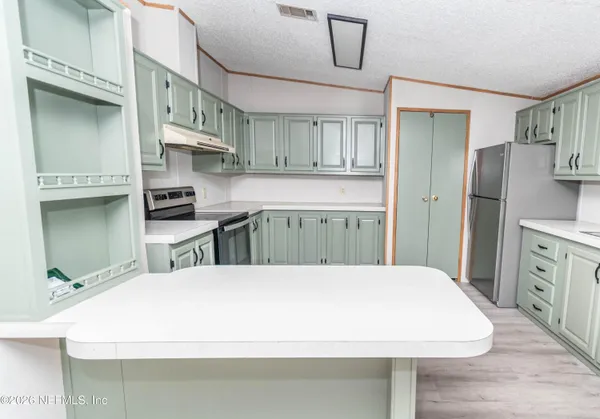 a kitchen with stainless steel appliances a white refrigerator a sink dishwasher a oven with white cabinets and wooden floor