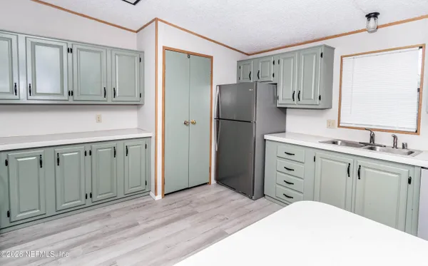 a kitchen with white cabinets and refrigerator