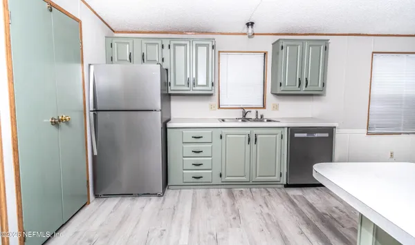 a kitchen with a refrigerator a sink and dishwasher with wooden floor