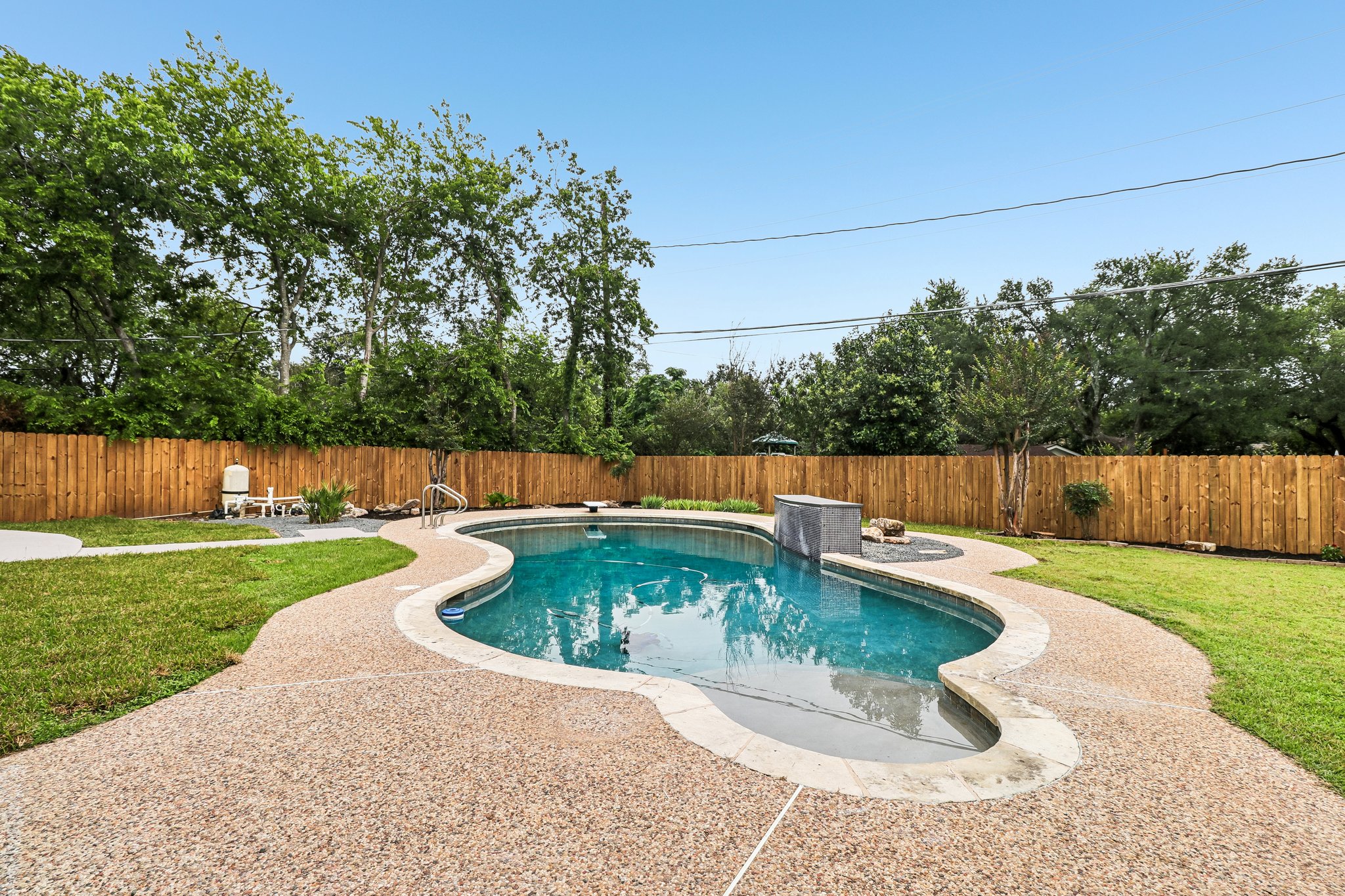 11809 Charing Cross Road Austin, TX 78759 - Photo 28 of 34 A private backyard oasis features a freeform pool surrounded by a gravel-textured patio and lush green lawn.