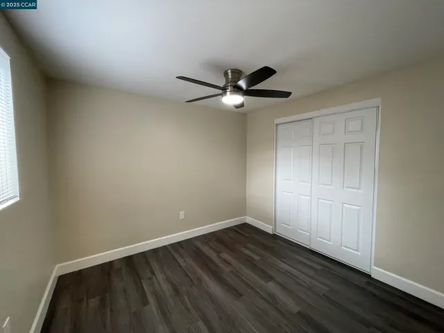 an empty room with a window and a fan