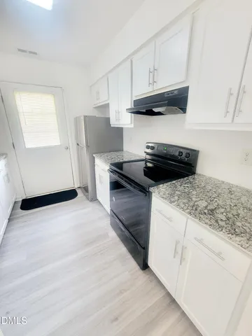 a kitchen with granite countertop a stove and a white cabinets