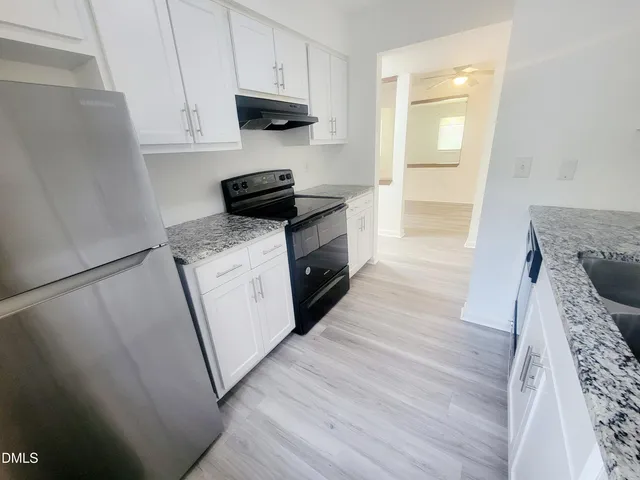 a kitchen with granite countertop a sink a stove and refrigerator