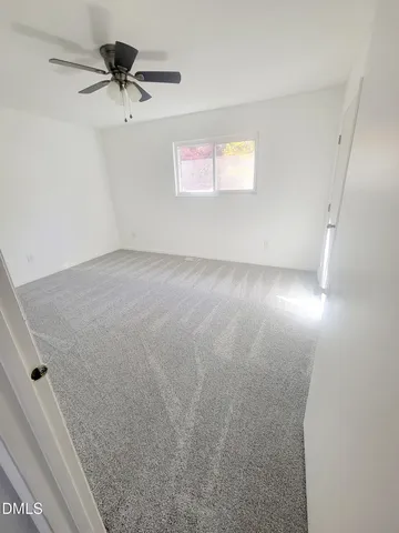 an empty room with a ceiling fan and window