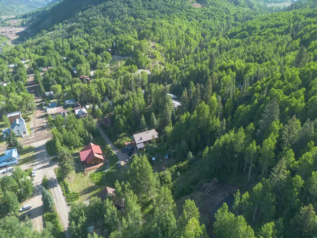 an aerial view of residential house with outdoor space and trees all around
