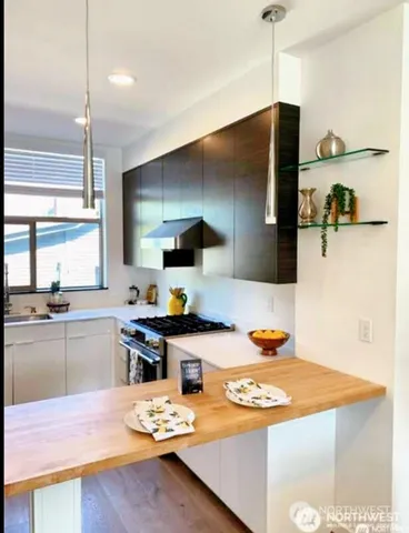 a kitchen with stainless steel appliances a stove a sink dishwasher and a refrigerator with wooden floor