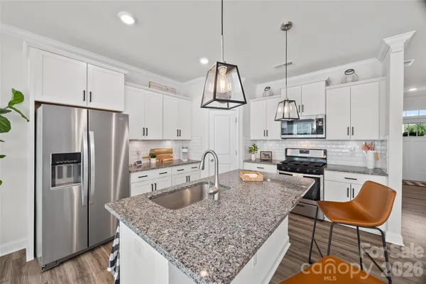 a kitchen with stainless steel appliances granite countertop a sink a stove a refrigerator cabinets and chairs