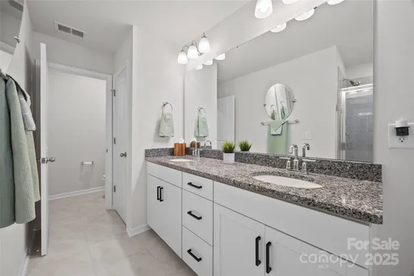 a bathroom with a granite countertop double vanity sink and a mirror