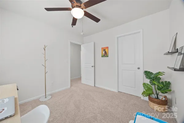 a view of a livingroom with a potted plant a ceiling fan and a bathroom