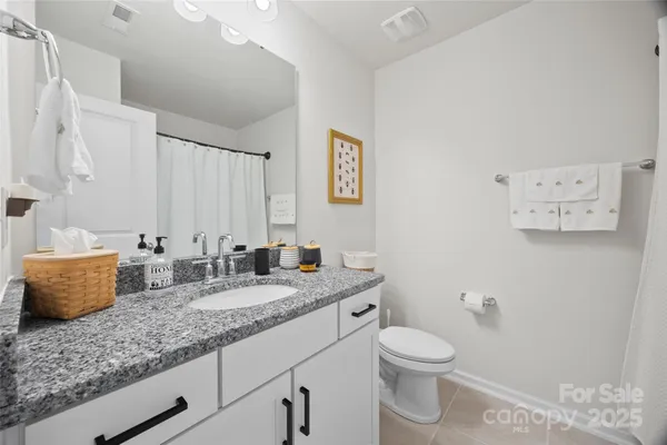 a bathroom with a granite countertop sink mirror vanity and toilet