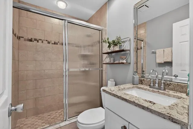 a bathroom with a granite countertop sink toilet and shower