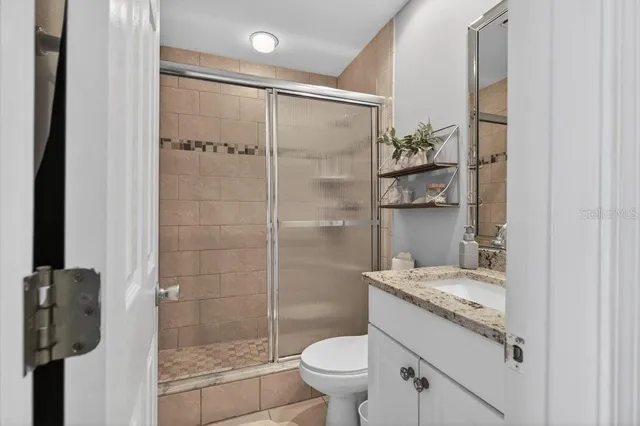 a bathroom with a granite countertop shower a toilet and a sink