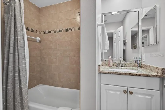 a bathroom with a granite countertop sink mirror and a bathtub