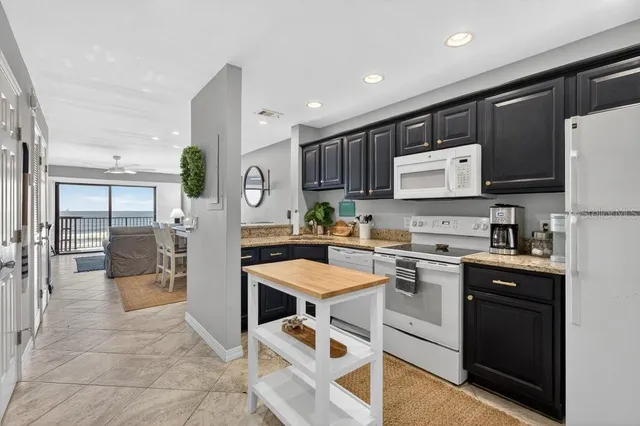 a kitchen with stainless steel appliances granite countertop a refrigerator oven a sink dishwasher and white cabinets next to a window