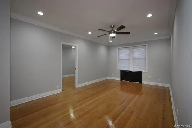 an empty room with wooden floor and ceiling fan