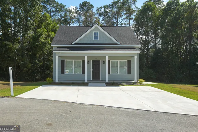 a front view of a house with a garden and trees