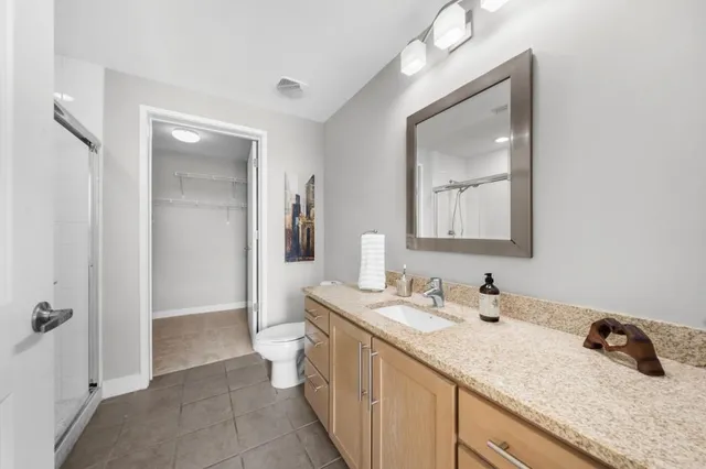 a bathroom with a double vanity sink and mirror with toilet