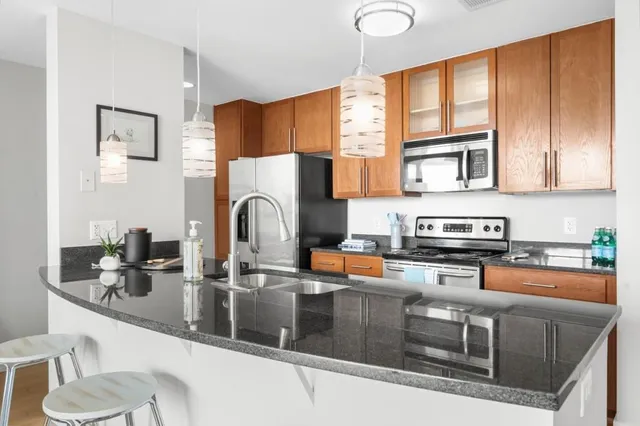 a kitchen with stainless steel appliances granite countertop a stove a sink and a microwave