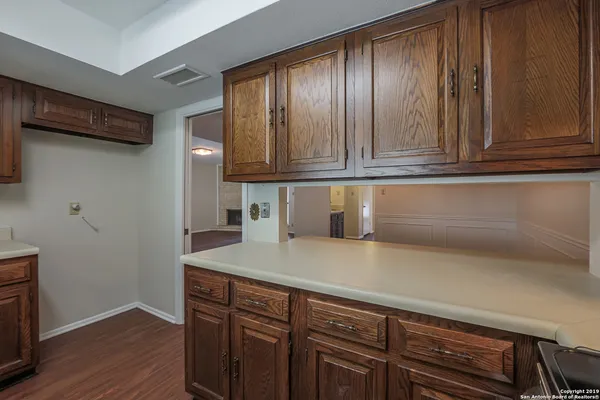 an empty room with wooden floor fireplace and chandelier