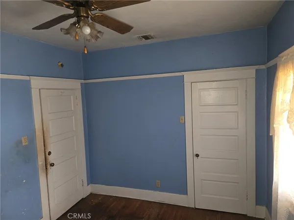 a view of empty room with wooden floor and fan