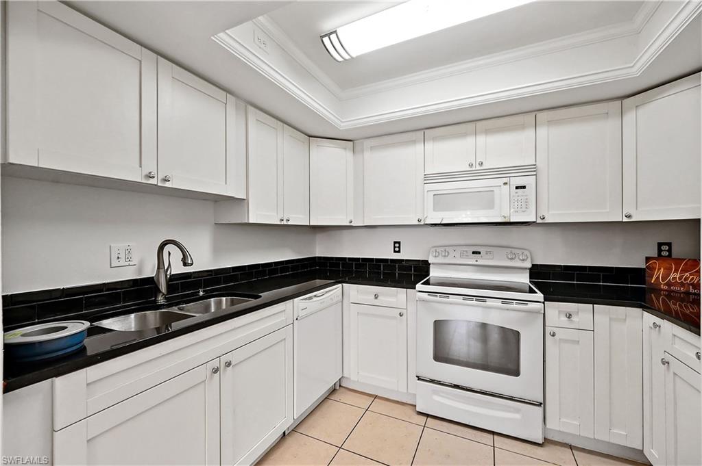 938 Augusta Boulevard, Unit D937 Naples, FL 34113 - Photo 16 of 27 a white kitchen with granite countertop white cabinets and white appliances