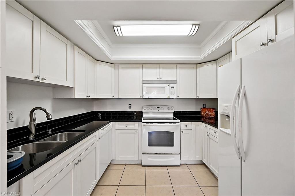 938 Augusta Boulevard, Unit D937 Naples, FL 34113 - Photo 17 of 27 a kitchen with white cabinets a sink and white appliances